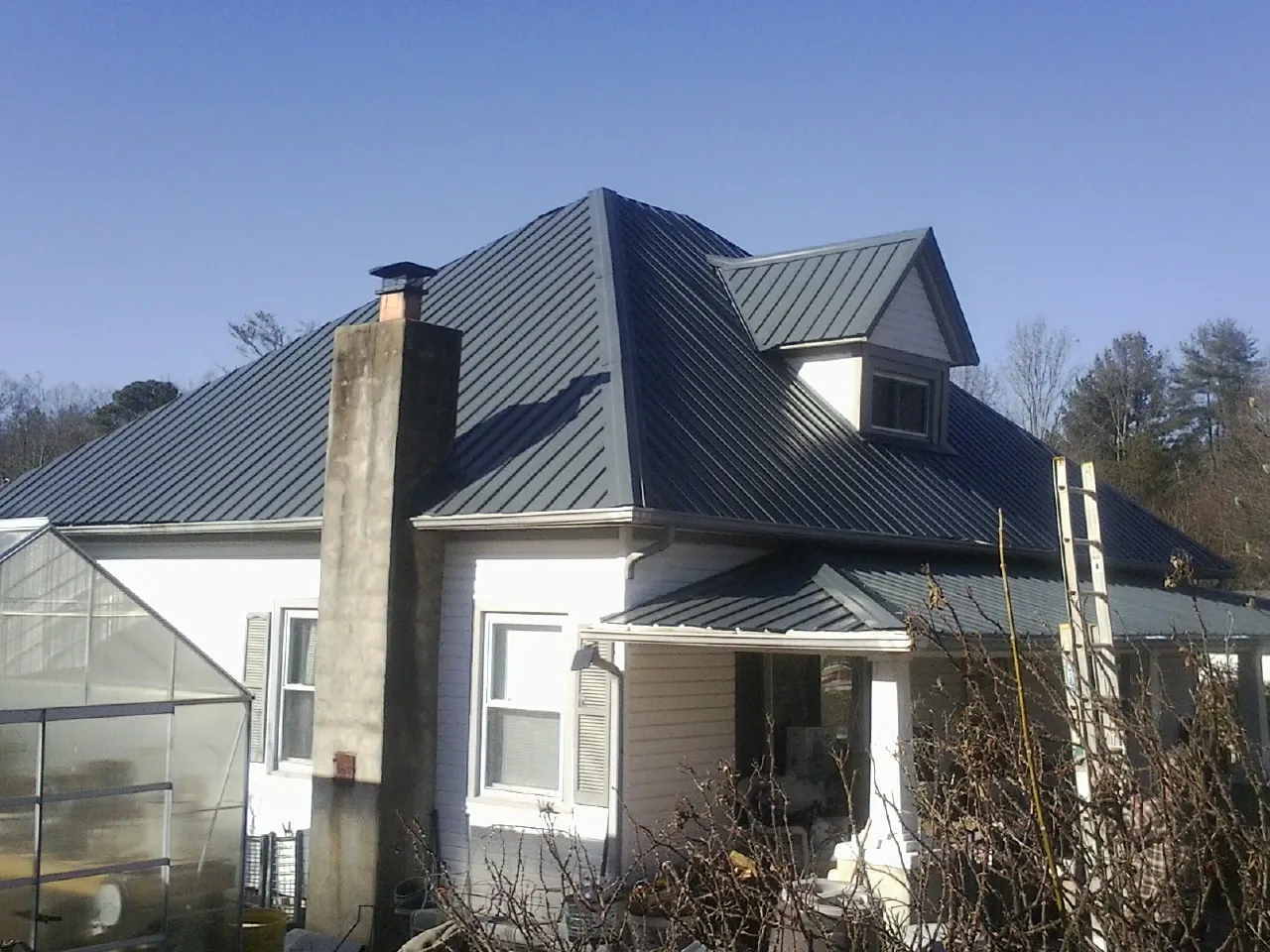Dark blue standing seam metal roof on a white farmhouse with dormer — Slate & Tile Roof Repair by Roofing Brothers in Fayette City