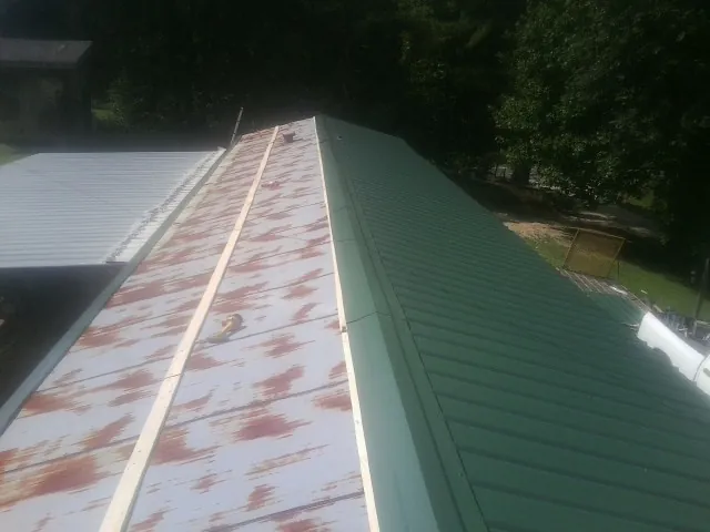 Old rusted panels beside newly installed green metal roofing — Wind Damage Roof Repair by Roofing Brothers in Fayette City