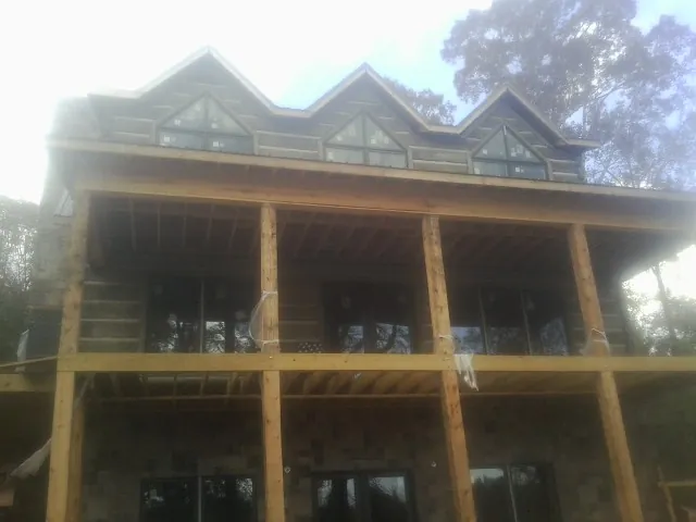 Dormers and porch framing on a large log home under construction — Roof Coating work by our crew in Fayette City
