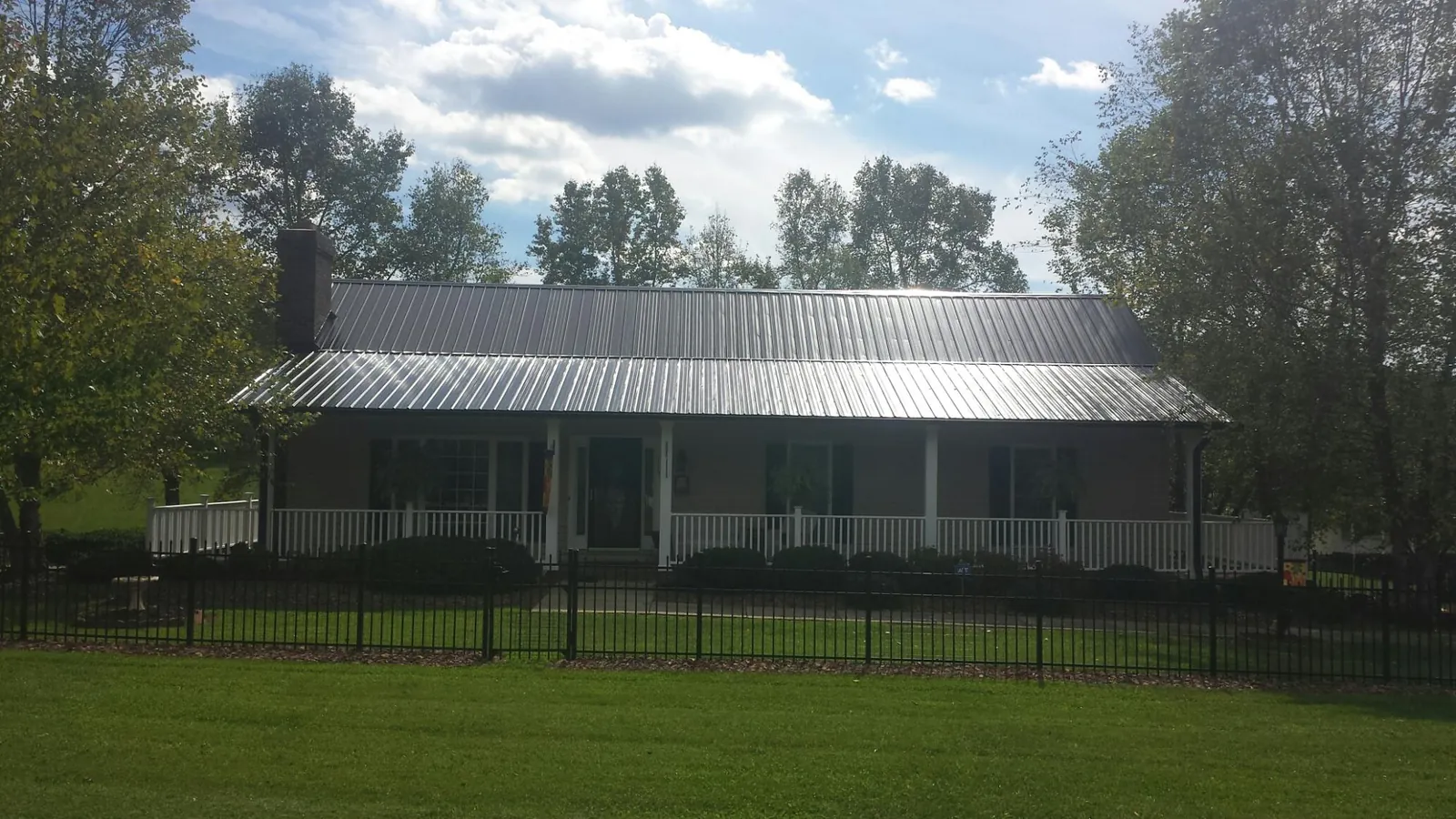 Gray metal roof on a brick ranch with a full width front porch — Gutter Guard Installation work by our crew in Fayette City