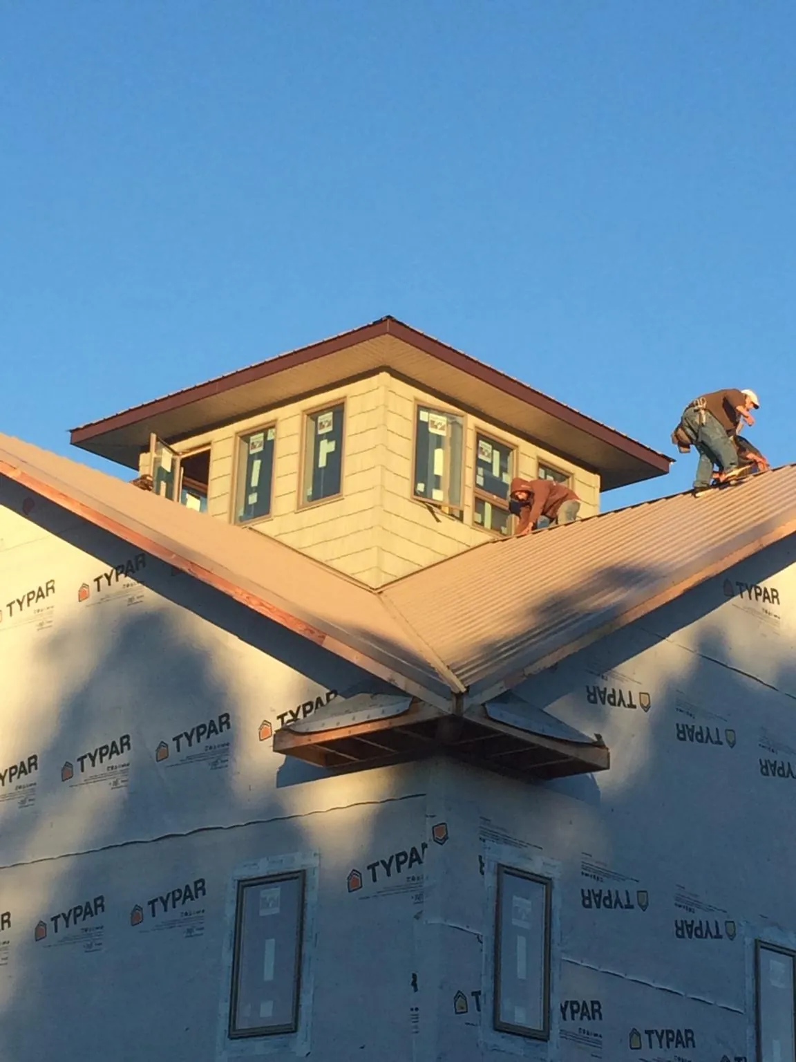 Roofers working around a rooftop cupola on a new metal roof at sunset — Roof Waterproofing in Fayette City by Roofing Brothers
